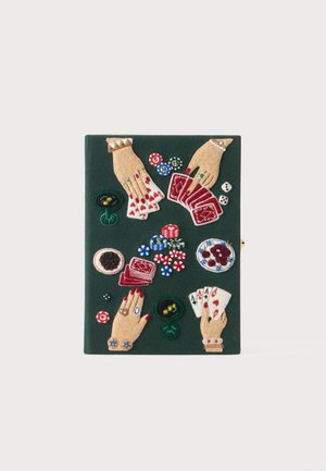Fire hænder med ringe og armbånd holder spillekort rundt om pokerchips, terninger, drikkevarer og tallerkener med snacks på en mørkegrøn overflade.