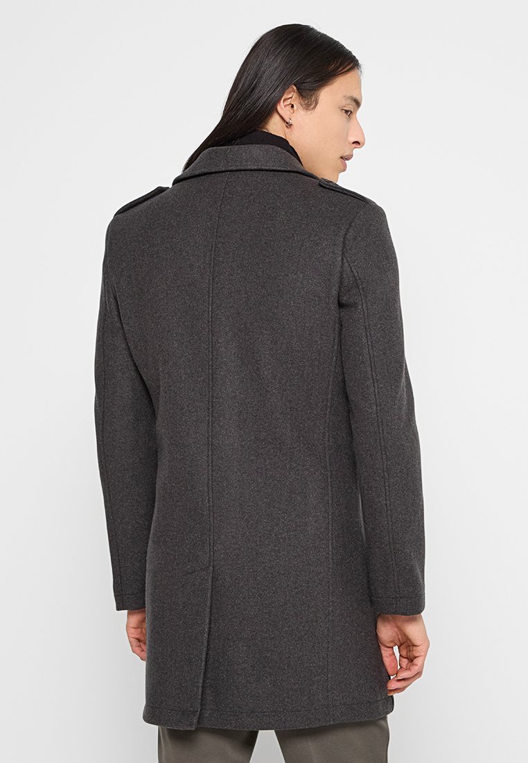 Abrigo de lana gris oscuro con un corte entallado, hombros estructurados y un cuello alto; cuenta con bolsillos laterales y un corte limpio.