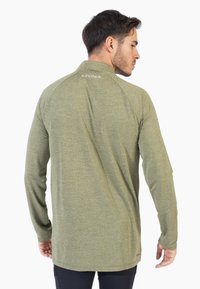 Camisa de manga larga en tela verde oliva con un patrón texturizado, dobladillo redondeado y logo de Spyder en el cuello. Diseño ligero y ajustado.