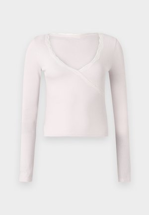 Blusa de manga larga de color rosa claro con textura acanalada y escote en V, acentuada con bordes de encaje blanco alrededor del cuello.