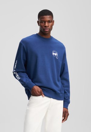 Marine sweatshirt met ronde hals, ribgebreide manchetten en zoom; voorzien van witte grafische opdruk op de borst en tekst op de linkermouw; gemaakt van zachte stof.