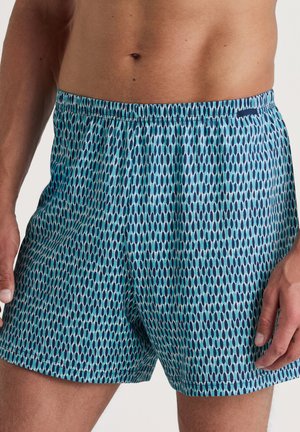 Shorts de bain colorés avec un motif bleu et turquoise, présentant une coupe décontractée, une taille élastique et une texture de tissu lisse.