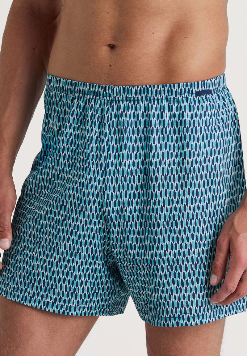 Kleurige zwembroek met een blauw en teal patroon, met een ontspannen pasvorm, elastische tailleband en een gladde stoftextuur.