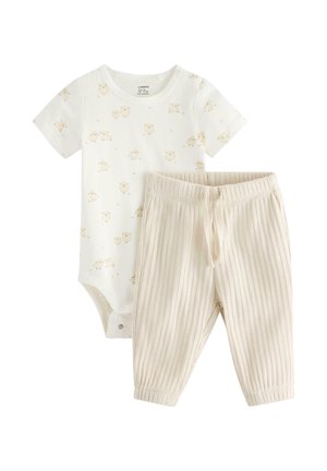Kortærmet hvid babybodystocking med lille fåreprint, kombineret med ribstrikkede cremefarvede babybukser med snøre i taljen.