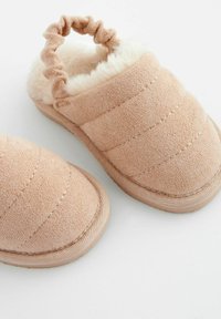 Chaussons en tissu rose à enfiler avec une doublure douce et pelucheuse, un dessus texturé et un détail de talon en tissu froncé. Semelle en caoutchouc plate pour le confort.