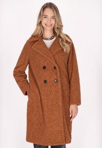 Palton texturat, de culoare maro, cu un design cu guler dublu, butoni mari negri și guler cu colțuri, având mâneci lungi și buzunare laterale.