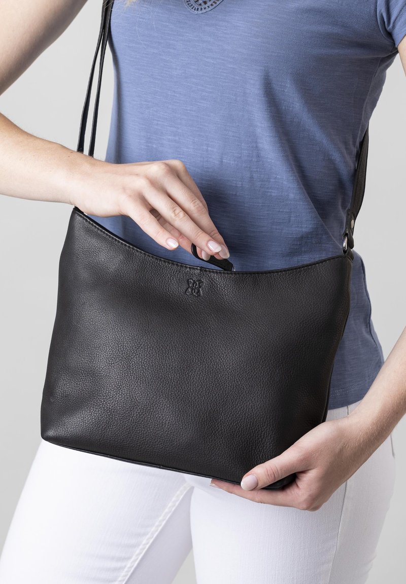 Black leather handbag with a textured surface, curved top, and a long adjustable strap. A small logo is embossed on the front.