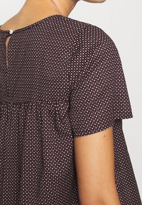 Bordeaux jurk met een gestructureerde stof met een klein hartpatroon, korte mouwen en een knoopsluiting aan de achterkant van de nek.