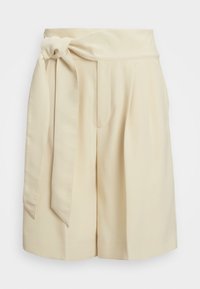 Kreemi värvi lühikesed püksid sileda kangaga, laia vöökoha, esise sõlme detaili ja kahe külgmise taskuga.