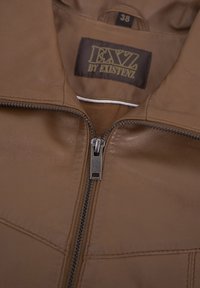 Braune Lederjacke mit frontalem Reißverschluss und dezenten Nähmustern. Das Innenetikett zeigt die Marke "EXZ by Existenz", Größe 38.