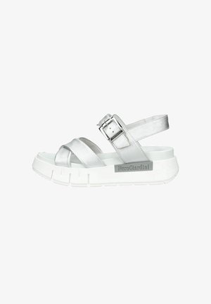 Sandalo metallizzato argento con due cinturini anteriori, cinturino regolabile alla caviglia con fibbia, suola bianca spessa e logo NeroGiardini sul lato.