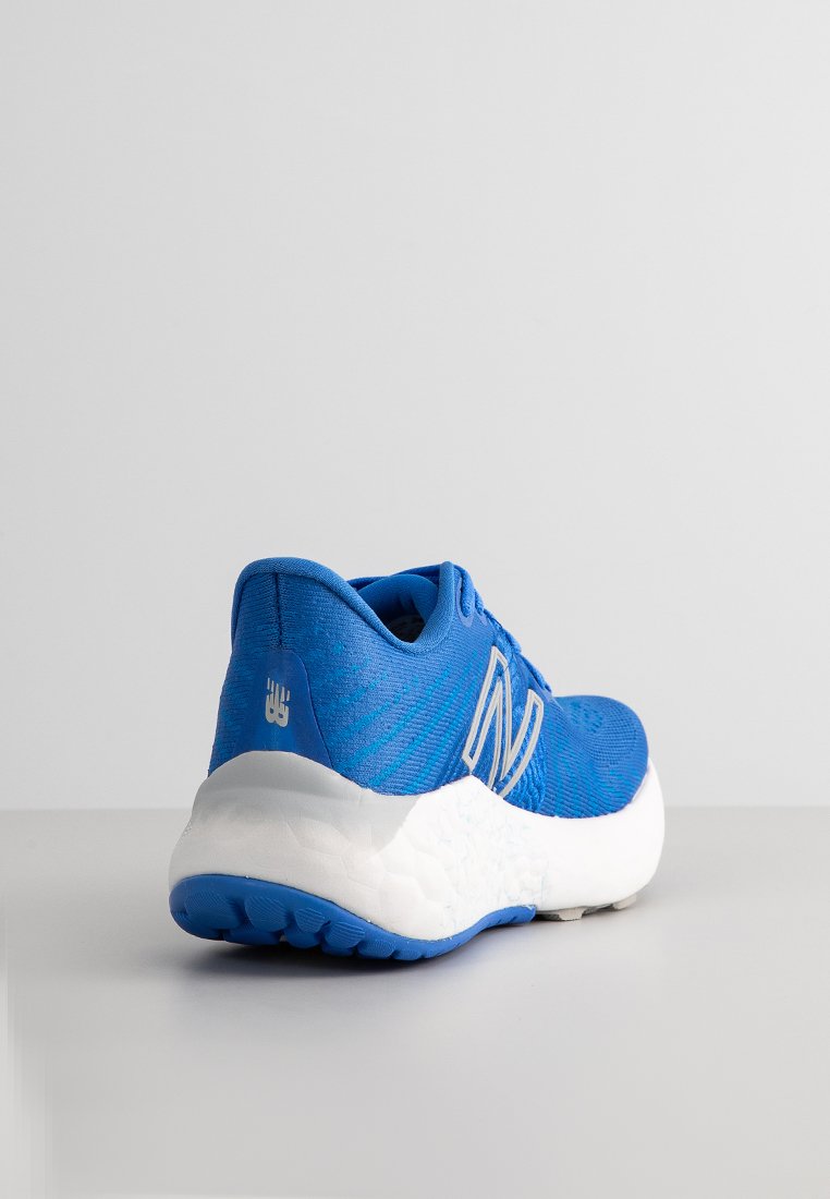 Blaues Sport-Schuhmodell mit einer strukturierten Oberseite, auffälligem weißen "N"-Logo und einer gepolsterten weißen Sohle mit blauen Akzenten.