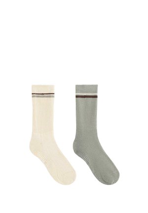 Pár hajóskapcsos bordás zokni, az egyik krémszínű, a másik szürke, mindkettőnél egy-egy barna és fehér vízszintes csík található a tetején.