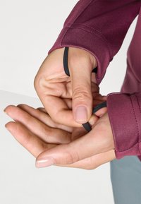 Maroon long-sleeve top with a thumb hole, featuring black elastic detailing at the cuff. Smooth texture and fitted design.