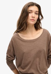 Bruine lange mouwen top met een wijde hals en een relaxte pasvorm, gemaakt van zachte, lichte stof en met licht opgerolde mouwen.