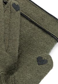 Close-up of olive green knit gloves with black heart-shaped patches on fingertips against a white background.