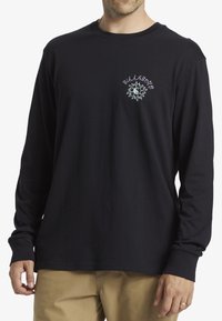 Camicia nera in cotone a maniche lunghe con un design grafico frontale che presenta testo e un motivo circolare. Collo rotondo semplice e vestibilità rilassata.