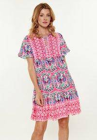 Vestito corto colorato con un motivo floreale rosa e verde, scollo a bottoni e maniche a sbuffo. Tessuto leggero con una vestibilità comoda.