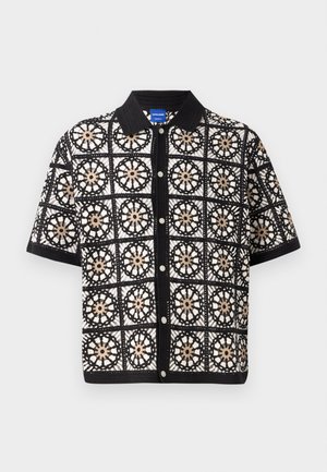 Juodasis trumpomis rankovėmis marškinis su sudėtingomis baltomis ir smėlinėmis gėlių nėrimo detalėmis, turintis sagų frontą ir plokščią apykaklę.