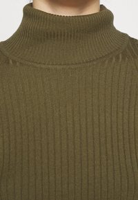 Olivgrüner, gerippter Rollkragenpullover mit enganliegender Passform und strukturiertem Stoff, ausgestattet mit einem runden Kragen und nahtlosen Schultern.