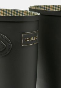 Črne gumijaste škornje za dež z oblogo v tartan vzorcu in prišitjem logotipa. Gladka textura, zaobljeni vrhovi in brez dodatnih poudarkov.