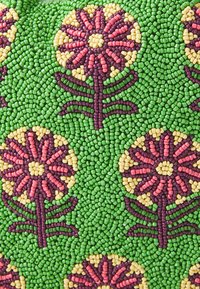 Perlenbesetzter Stoff mit lebhaften Blumenmustern in Pink, Gelb und Grün auf grünem Hintergrund, mit komplexen Texturen und Formen.
