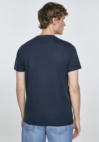 Tamsiai mėlynas medvilninis marškinėliai su trumpomis rankovėmis, apvaliu iškirpimu ir tiesiu kirpimu, pasižymintys lygiu paviršiumi ir be matomo logotipo.