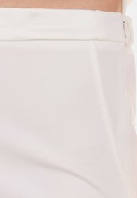 Pantaloni bianchi su misura realizzati in tessuto liscio, con una vita piatta e dettagli di cucitura discreti. Design semplice senza motivi.