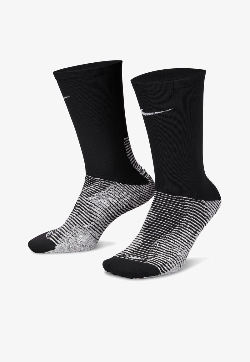 Sosete atletice negre cu textură țesută, cu un logo alb Nike și un model în dungi gri în jurul zonei piciorului.
