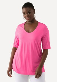 Roze kortmouwen top met een ronde halslijn, gemaakt van zachte stof, met een relaxte pasvorm en een gladde textuur. Gestyled met witte broeken.