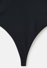 Černé bikiny ve spodní části vyrobené z hladké tkaniny, s trojúhelníkovým tvarem, tenkými bočními popruhy a minimálním designem pokrytí.