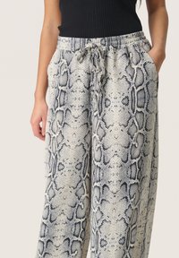 Wijduitlopende broek met een zwart-wit slangenprint, voorzien van een elastische tailleband met een trekkoord en zijzakken.