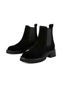 Black suede Chelsea boots featuring elastic side panels, a chunky black sole, and pull tabs for easy wear. Flat, rounded toe design.