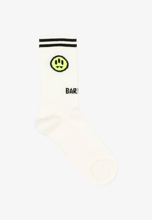 Witte sok met twee zwarte strepen aan de bovenkant, een neon groene smiley met tanden, en gedeeltelijke zwarte tekst "BAR" zichtbaar.