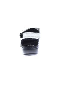 Black platform sandal featuring a white adjustable strap, smooth surface, and a rounded toe design with cushioned insole.