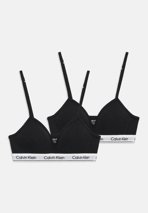 Zwei schwarze Calvin Klein Bralettes mit dünnen verstellbaren Trägern und weißen elastischen Bändern mit Markenaufdruck auf einem schlichten Hintergrund.