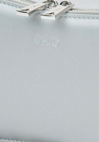 Srebrna kosmetyczka z gładkiej tkaniny, z zamknięciem na zamek i wytłoczonym logo "estro". Elementy metalowe mają eleganckie wykończenie.