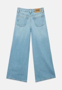 Bredde ben blå denimbukser med lys vask, med et beigefarget lærmerke på midjen og to baklommer.