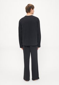 Zwarte lange mouwen top en bijpassende brede broek, eenvoudig ontwerp, zachte stof, comfortabele pasvorm, minimale stiksel details, geen zichtbaar logo.