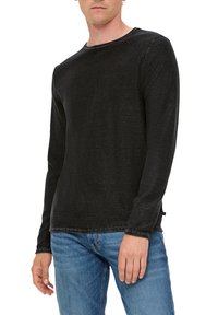 Zwarte longsleeve t-shirt van gestructureerde stof, met een ronde hals en een casual pasvorm, gecombineerd met blauwe denim jeans.