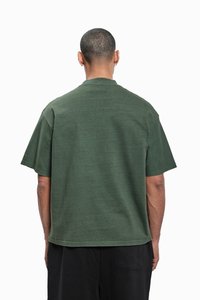 Dark green oversized t-shirt made of cotton, featuring short sleeves and a round neck, with a relaxed fit and no visible patterns or accents.