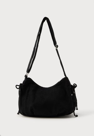 Bolsa de ombro em corduroy preto com uma forma curva, alça ajustável e fechos de cordão de ambos os lados para ajuste de tamanho.