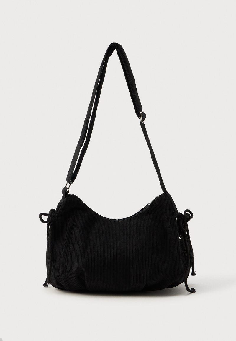 Borsa a spalla in corduroy nero con forma curvata, tracolla regolabile e chiusure a coulisse su entrambi i lati per la regolazione della dimensione.