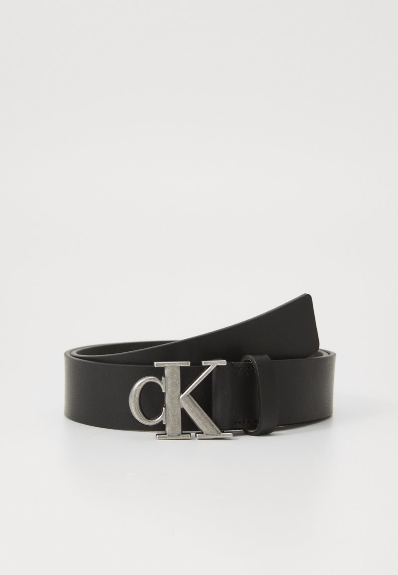 Čierny kožený opasok s sivým „CK“ logom na pracke, hladkou textúrou a klasickým dizajnom pre nastaviteľné prispôsobenie.