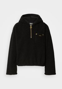 Hoodie preto, peludo, com um fecho de correr de um quarto, capuz forrado e um bolso frontal. Apresenta acessórios em dourado e um exterior suave e texturizado.