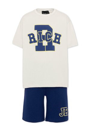 Witte korte mouwen T-shirt met grote blauwe "RICH" tekst en donkerblauwe korte broek met geel omrande "JB" letters op het linkerbeen.