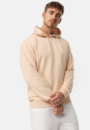 Sudadera con capucha en color melocotón claro, con cordón ajustable, puños y dobladillo acanalados. Presenta un pequeño logotipo en el pecho. Tejido suave y de textura lisa.