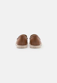 Bruine leren schoenen met een gladde textuur, afgeronde achterkant en lichtgekleurde rubberen zolen. Kenmerken subtiele branding op de hiel.