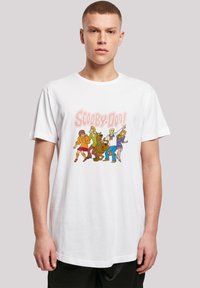 Hvit bomull t-skjorte med et fargerikt grafisk motiv av Scooby-Doo karakterer, inkludert Scooby og gjengen, i dristig, tegneseriestil.