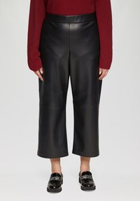 Zwarte leren culottes met een wijde pijpontwerp, voorzien van een gladde textuur en een strakke afwerking. Gecombineerd met glanzende zwarte loafers.